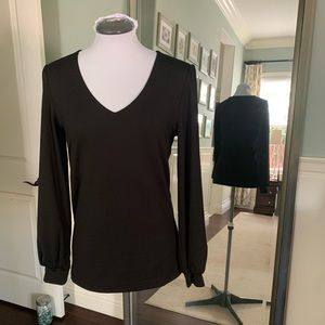 Small black v-neck top with slightly puffed sleeves.